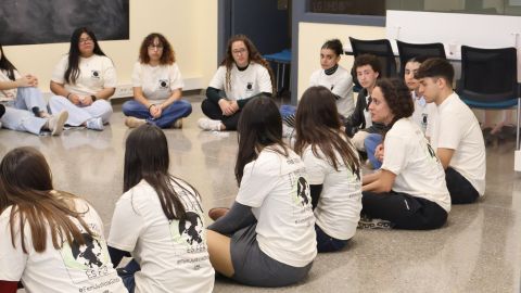 Grup de persones assegudes al terra en rotllana amb la samarreta de la FAS.